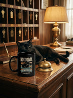 Mug noir Not Today sur le comptoir de la réception du motel, à côté d'un chat noir