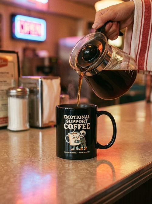 Mug noir Emotional Support Coffee rempli de café au comptoir d'un diner rétro