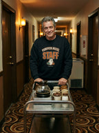 Sweat noir Pumpkin Motel Staff porté avec un chariot de room service dans un couloir de motel
