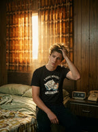 T-shirt noir 5 More Minutes porté au réveil dans une chambre de motel